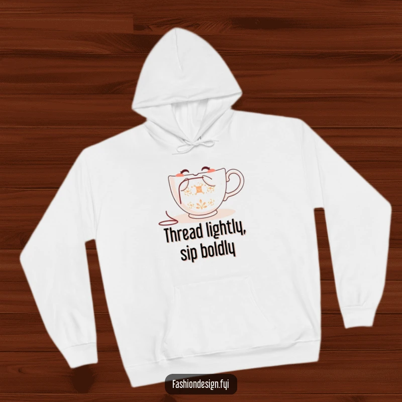 Funny teacup hoodie, smiling while embroidering with needle and thread, cozy and warm, perfect for crafters.